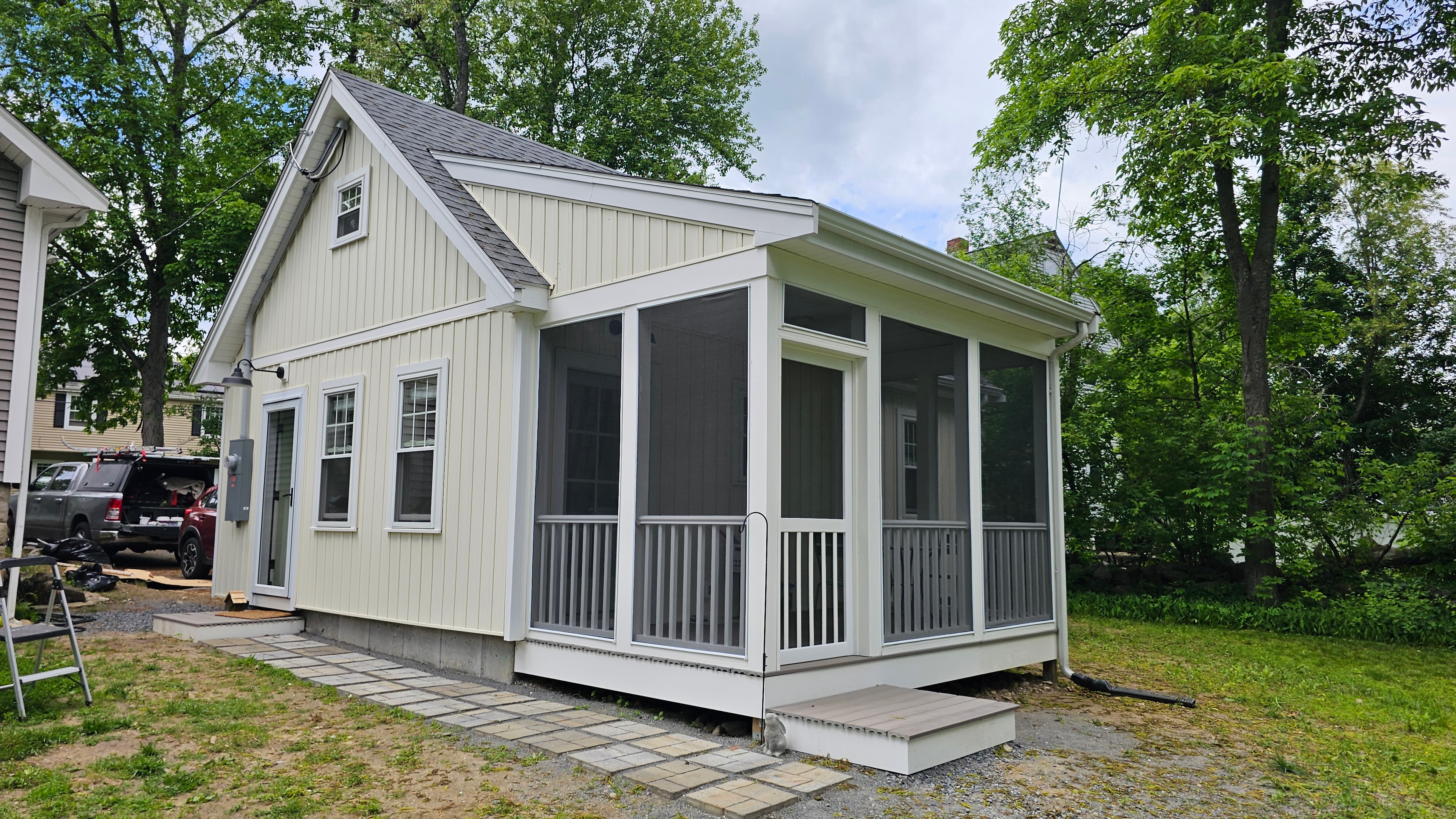 Full exterior of the Medway ADU showing the building, screened porch addition, white trim, windows with casings, and surrounding trees.