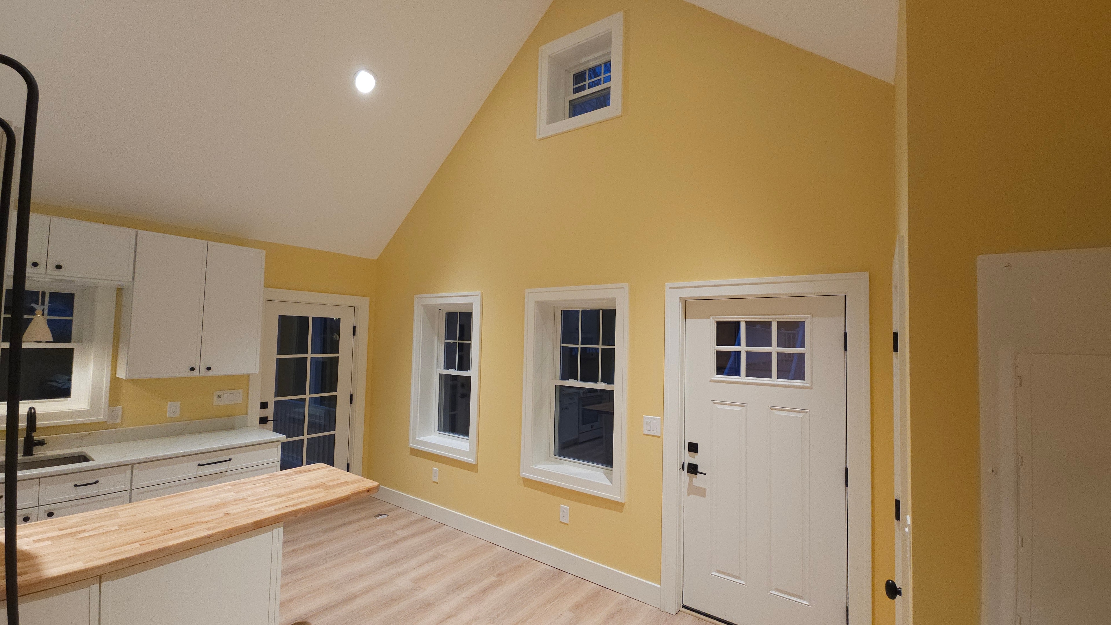 Cathedral ceiling and window wall in the Medway ADU kitchen, showing yellow walls, white trim, and window casings.