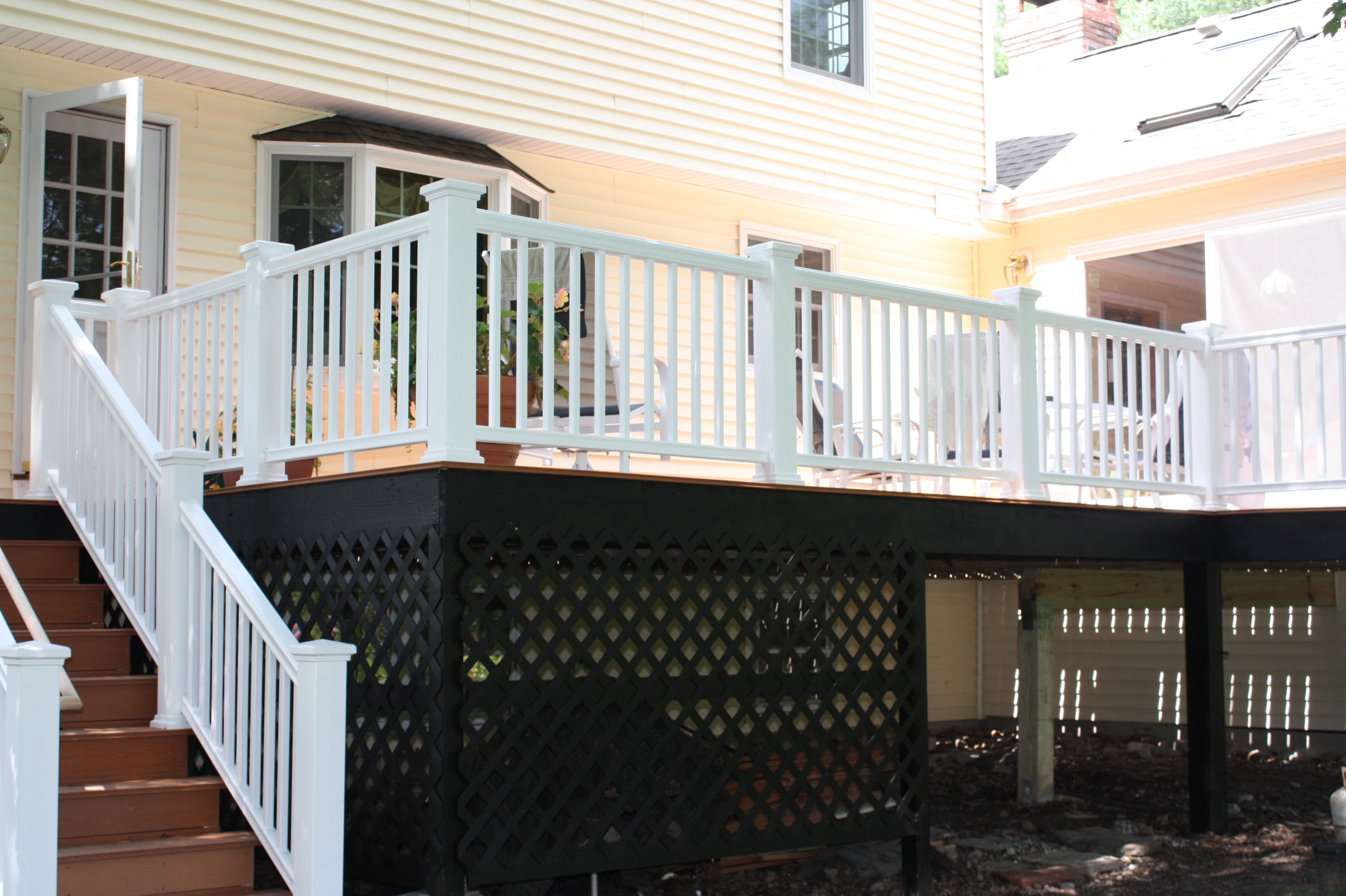 Completed deck rebuild — white vinyl railing and black lattice skirting — MetroWest MA