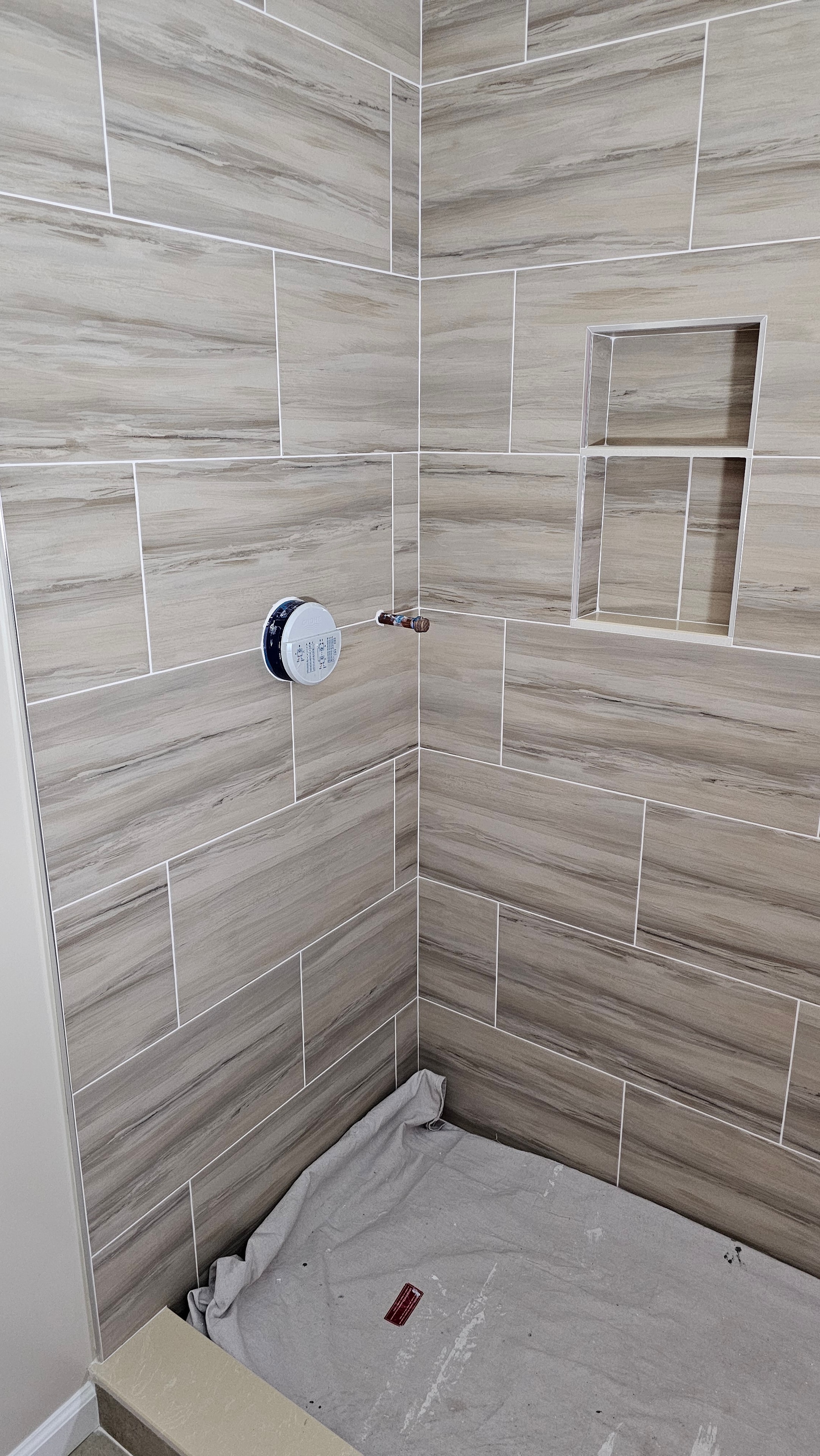 Shower tile installation complete — pre plumbing fixture install