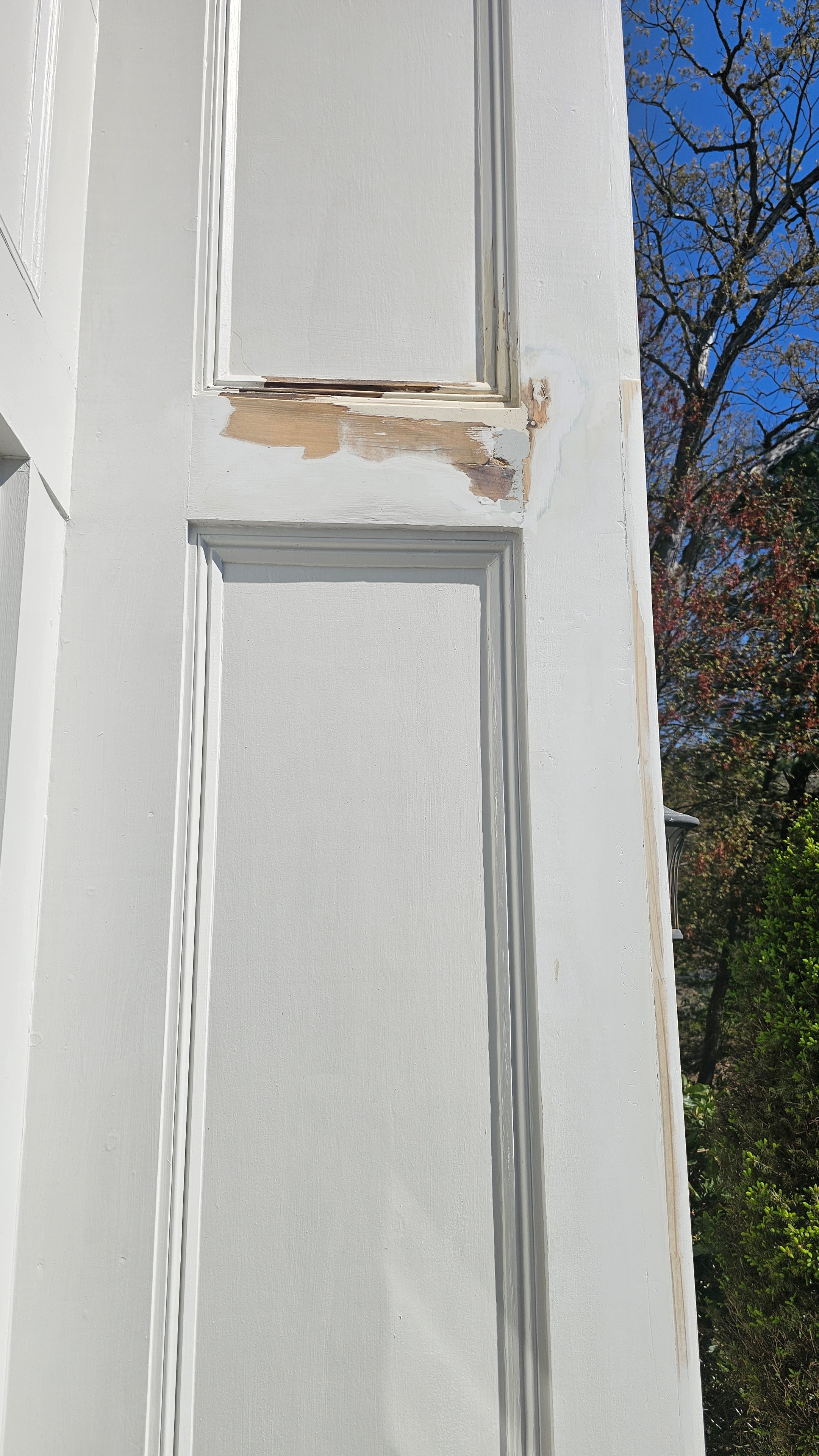 White exterior trim panel on the Natick property showing localized wood rot exposed at a corner joint during epoxy repair work.