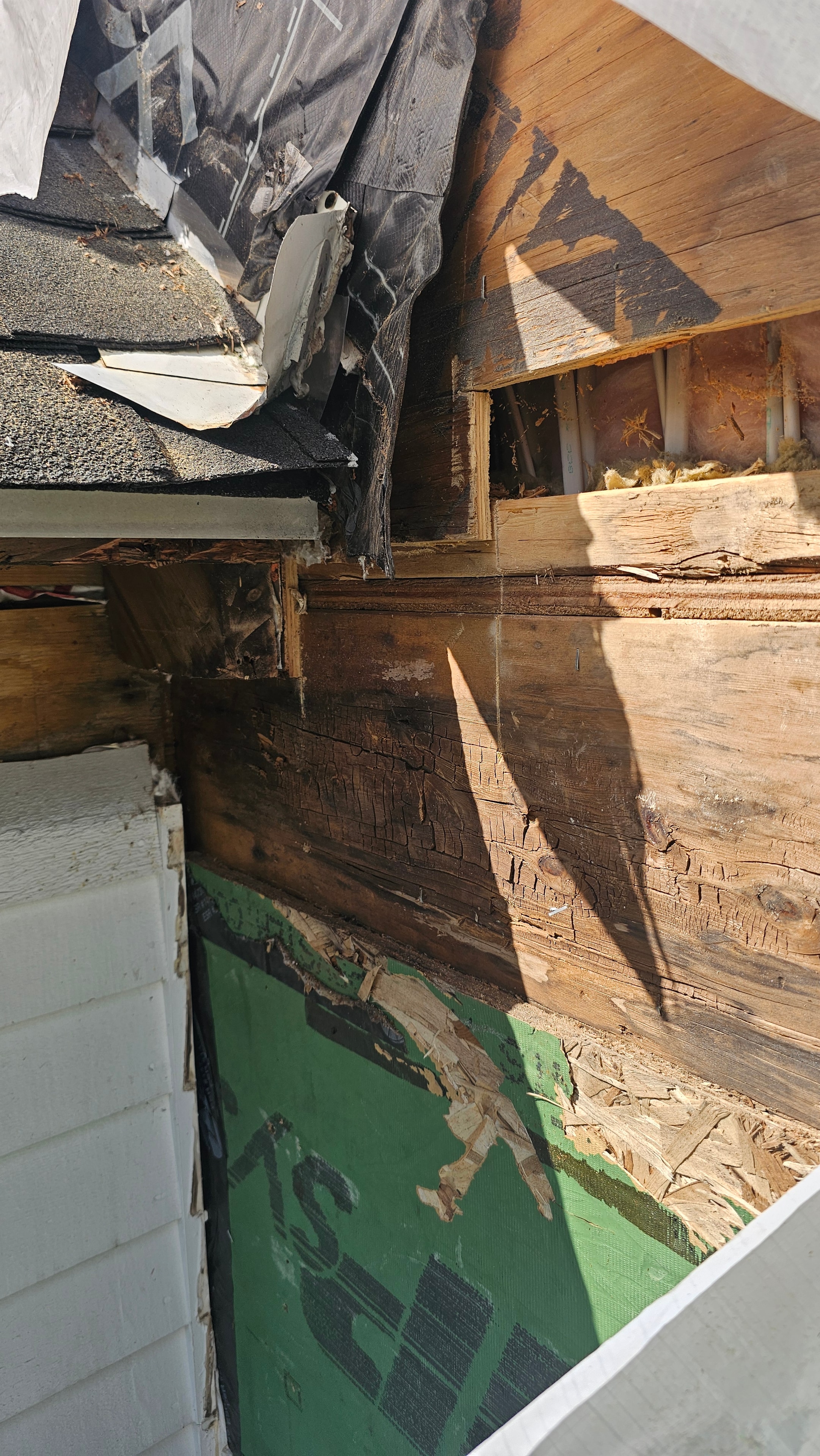 Close-up of deteriorated framing and sheathing on the Natick exterior restoration, showing rotted wood structure concealed behind the original exterior finish.