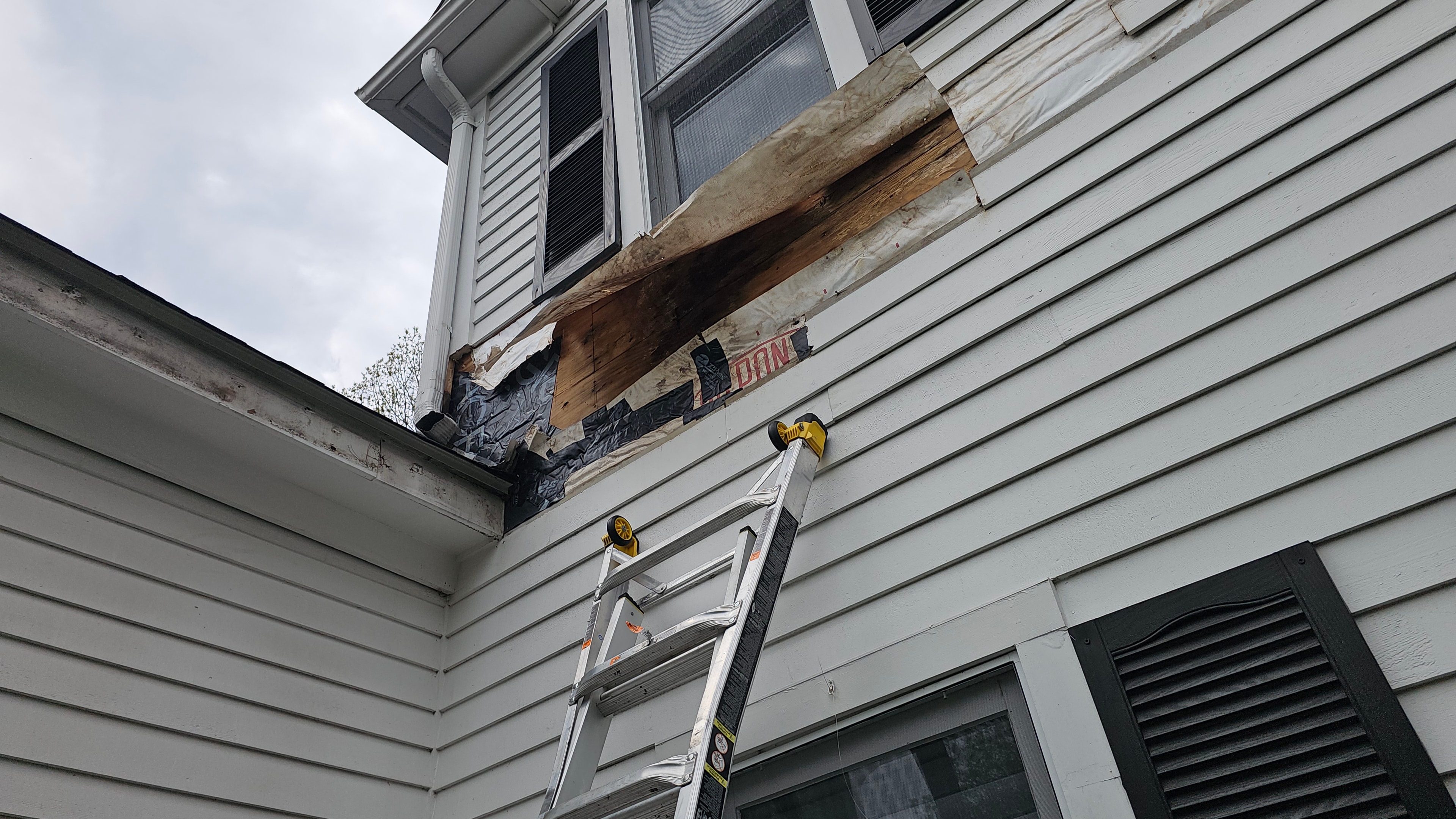 Exterior of the Natick property with siding removed, exposing the wall structure and ice-and-water barrier beneath.